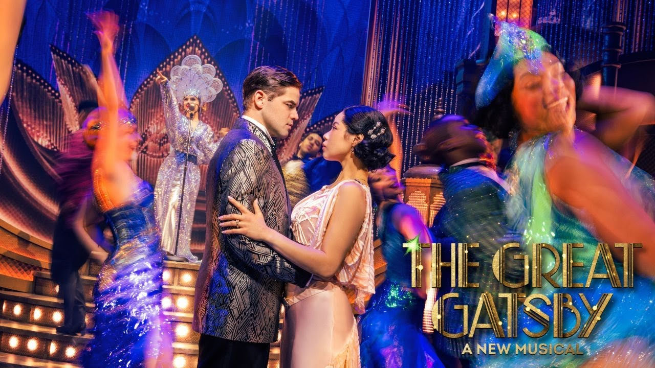 Jeremy Jordan and Eva Noblezada as Jay Gatsby and Daisy Buchanan embrace on a dance floor, at an extravagant party, looking into each other's eyes very seriously